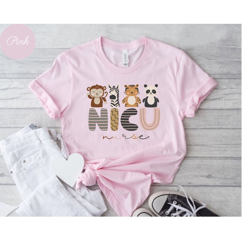 Pode incluir: Uma t-shirt rosa claro com o texto "NICU nurse" e gr&aacute;ficos de animais. O design inclui um macaco, uma zebra, um tigre e um panda. A t-shirt &eacute; combinada com jeans brancos e um par de t&eacute;nis pretos e brancos.