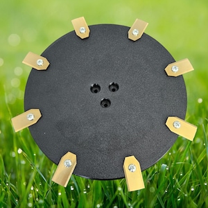 Könnte beinhalten: Eine schwarze, kreisförmige Klinge mit acht goldfarbenen Klingen, die um den Umfang herum befestigt sind. Die Klingen sind mit Schrauben befestigt. Die Klinge ist für die Verwendung mit einem Rasenmäher konzipiert.