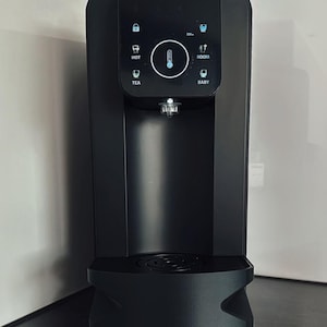 Könnte beinhalten: Schwarzer Wasserspender mit digitalem Bedienfeld. Das Panel zeigt Symbole für heißes Wasser, Tee, Raumtemperatur und Babyflascheneinstellungen. Ein Thermometer wird in der Mitte angezeigt. Der Spender hat ein schlankes, modernes Design.
