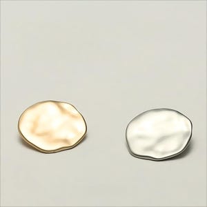 Può includere: Due orecchini in metallo di forma irregolare, uno dorato e uno argentato.