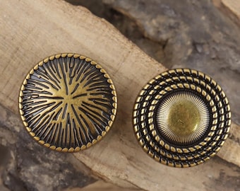 May include: Two antique brass-coloured buttons. One button features a sunburst design, while the other has a rope-like border around a central circle. Both buttons are round and have a vintage aesthetic.