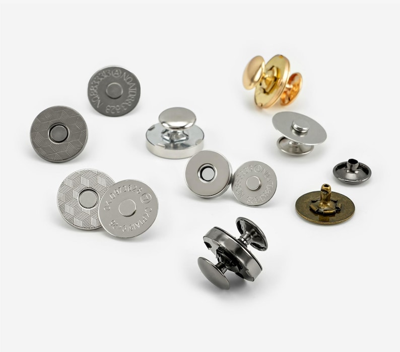 May include: Assortment of magnetic snaps and metal buttons in silver, gold, and bronze finishes. The snaps have a flat, circular design with a raised centre. The buttons have a round, domed shape with a small post on the back.