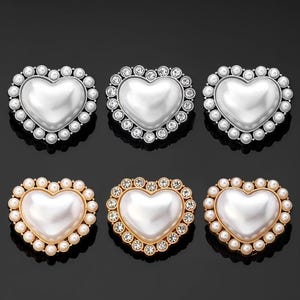 Op de afbeelding: Zes hartvormige broches met parel- en strassaccenten. Drie broches zijn zilver, twee zijn goud en één is een mix van zilver en goud.