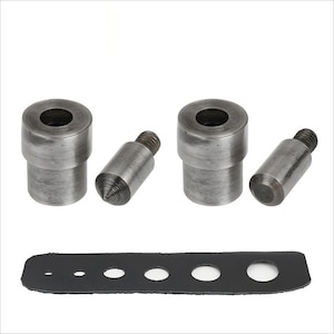 Op de afbeelding: Een set metalen gereedschappen voor leerbewerking, waaronder twee cilindrische ponsen, twee schroefpalen en een zwarte leren strip met gaten van verschillende afmetingen. De gereedschappen zijn gemaakt van zilverkleurig metaal.