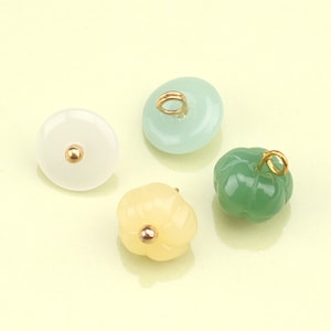 May include: Four jade pendants with gold accents. The pendants are in the shapes of a pumpkin, a flower, and two circles.