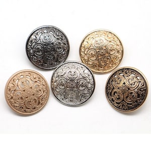 May include: Five decorative round buttons in various metallic finishes: silver, gold, bronze, and gunmetal. Each button features an ornate, openwork design with a central pattern and surrounding swirls. The buttons are arranged on a white background.