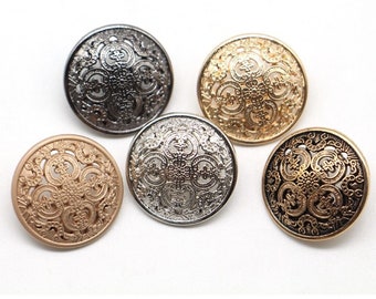 May include: Five decorative round buttons in various metallic finishes: silver, gold, bronze, and gunmetal. Each button features an ornate, openwork design with a central pattern and surrounding swirls. The buttons are arranged on a white background.