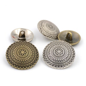Peut inclure: Quatre boutons décoratifs avec un design circulaire et orné. Deux boutons sont argentés et deux sont bronze.