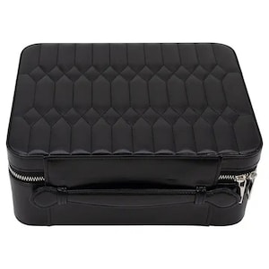 May include: A black quilted leather travel case with a silver zipper and a handle. The case has a diamond-shaped pattern.