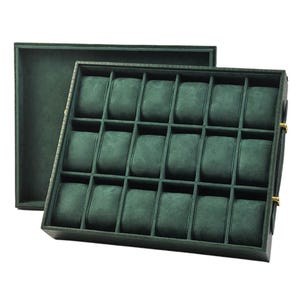 Peut inclure: Un écrin à montres vert foncé de forme rectangulaire avec un couvercle amovible. L'intérieur comporte de multiples compartiments rembourrés pour ranger les montres. L'étui est conçu pour contenir plusieurs montres, avec une doublure douce et texturée.