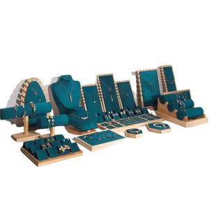 Peut inclure: Un présentoir à bijoux en bois avec plusieurs niveaux et compartiments. Le présentoir est recouvert de velours turquoise et présente une variété de bijoux, notamment des colliers, des bracelets, des boucles d'oreilles et des bagues.