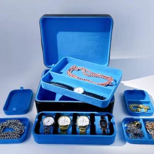 May include: A blue and black jewelry box with multiple compartments for storing watches, necklaces, and other jewelry. The box has a velvet lining and a zipper closure.
