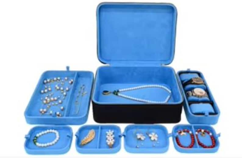 May include: A blue velvet jewelry box with multiple compartments for storing necklaces, earrings, bracelets, and watches. The box has a hinged lid and a soft blue interior.