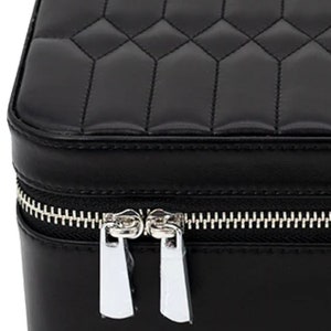May include: Black quilted leather jewelry box with a silver zipper and two zipper pulls.