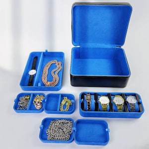 May include: A black leather watch and jewelry box with blue velvet lining. The box is open and shows multiple compartments for storing watches, necklaces, and other jewelry.