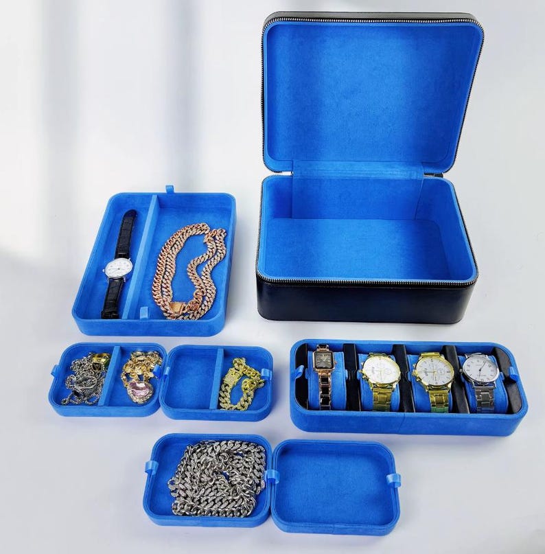 May include: A black leather watch and jewelry box with blue velvet lining. The box is open and shows multiple compartments for storing watches, necklaces, and other jewelry.