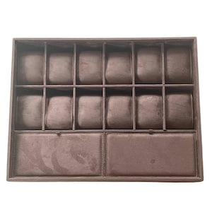 May include: A brown watch display case with multiple compartments. The case has a rectangular shape and is divided into sections for storing watches. The interior is lined with a soft, plush material to protect the watches.
