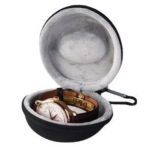 May include: A black, zippered watch case with a gray, plush interior. Inside, a gold-toned wristwatch with a brown leather band is visible. The case has a small carabiner clip attached.