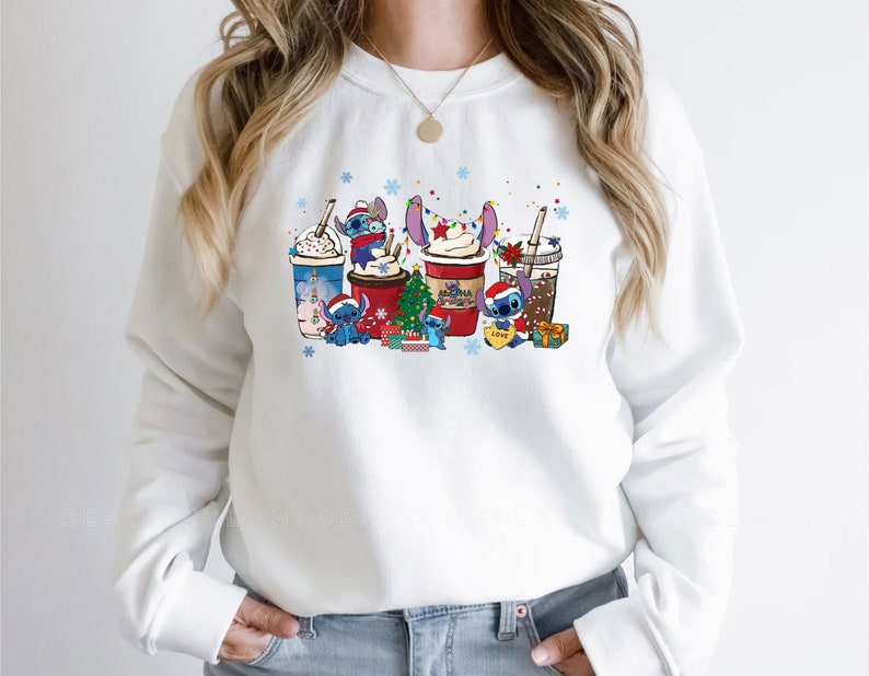 Peut inclure: Sweat-shirt blanc avec un motif sur le th&egrave;me de No&euml;l repr&eacute;sentant Stitch de Lilo & Stitch. Le motif comprend Stitch tenant une tasse de caf&eacute;, un sapin de No&euml;l et des cadeaux.