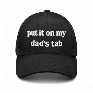 Può includere: Un cappellino da baseball nero in stile trucker con pannello frontale strutturato e pannelli posteriori in rete. La parte anteriore del cappellino presenta il testo ricamato in bianco "put it on my dad's tab" in un carattere sans-serif.