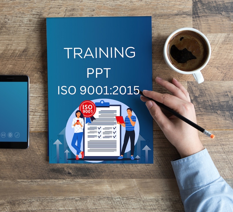 Op de afbeelding: Een blauwe trainingspresentatie over ISO 9001:2015 met een checklist en twee cartoonfiguren. De presentatie ligt op een houten tafel met een kop koffie en een smartphone.