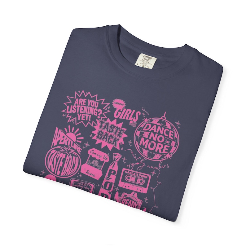 May include: Navy blue t-shirt with a pink graphic design featuring phrases like "ARE YOU LISTENING?" and "DANCE NO MORE." The design includes a disco ball, a cassette tape, and the words "AMERICAN GIRLS."