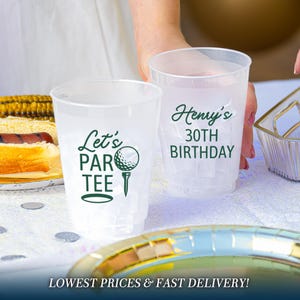 May include: Two clear, frosted plastic cups featuring dark green text and graphics. One cup displays the text 'Let's PAR TEE' with a golf ball on a tee. The second cup features the text 'Henry's 30TH BIRTHDAY' in a bold, dark green font.