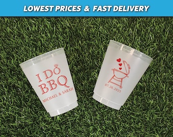 May include: Two clear plastic cups with red text and designs. One cup says "I Do BBQ" with the names "Michael & Sarah" below. The other cup has a grill with hearts and the date "07.26.2025".