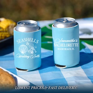 May include: Two light blue foam can coolers with white printed text and graphics. One cooler features the text SEASHELLS & Wedding Bells with a seashell and bell illustration. The other features Samantha's BACHELORETTE MIAMI BEACH, FL.