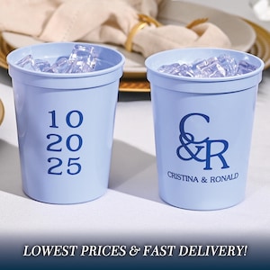May include: Two blue plastic cups with ice. One cup has the numbers 10, 20, and 25 printed on it. The other cup has the letters C & R printed on it, along with the text "Cristina & Ronald".