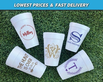 May include: Five white foam cups featuring various custom prints. One has a red circle with names, one a blue monogram with text, one a gold ornate monogram, one brown text with an arrow, and one a purple letter T inside a laurel wreath.