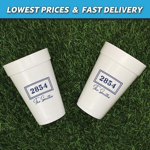 May include: Two white foam cups with a blue rectangular design that includes the number 2854 and the name "The Smiths". The cups are on a bed of green grass. The top of the image has the text "LOWEST PRICES & FAST DELIVERY".