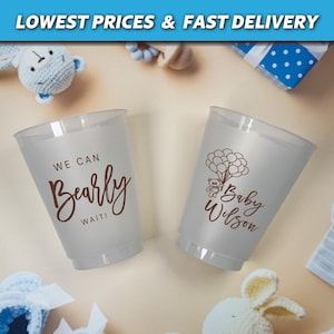 Puede incluir: Dos vasos de pl&aacute;stico transparentes con texto marr&oacute;n. Un vaso dice "We can Bearly Wait!" y el otro vaso dice "Baby Wilson" con un peque&ntilde;o oso sosteniendo globos.