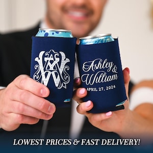 May include: Two navy blue can coolers with white embroidery. One cooler features a monogram with the letters "A" and "W" intertwined. The other cooler has the text "Ashley & William" and the date "April 27, 2024".