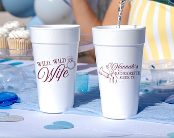 May include: Two white foam cups with maroon text and graphics. The left cup features the text WILD, WILD Wife with a diamond ring icon. The right cup displays the text Hannah's BACHELORETTE AUSTIN, TX with a graphic of two cowboy boots.