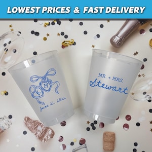 May include: Two frosted plastic cups with blue ink designs. One cup has a ribbon and heart design with the initials "K M" and the date "June 21, 2026". The other cup says "MR. + MRS. Stewart".