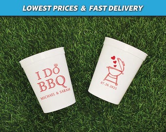 May include: Two white plastic stadium cups featuring red printed graphics. One cup displays the text I DO BBQ with a diamond ring icon and the names MICHAEL & SARAH. The other cup shows a barbecue grill icon with hearts and the date 07.26.2025.