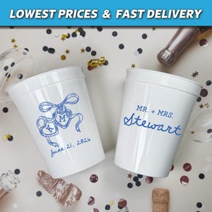 May include: Two white plastic cups with blue text and designs. One cup has a ribbon design with initials and the date "June 21, 2026." The other cup says "MR. + MRS. Stewart." Confetti and champagne bottles surround the cups.