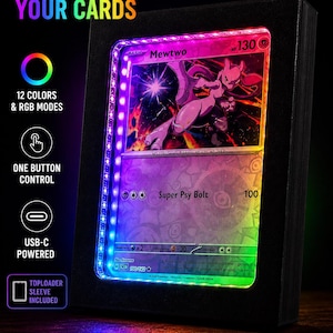 May include: A black display case with a Pokémon card illuminated by a multi-colored LED light strip. The card features a purple Mewtwo character. Text on the case reads "LIGHT UP YOUR CARDS", "12 COLORS & RGB MODES", and "TOPLOADER SLEEVE INCLUDED".