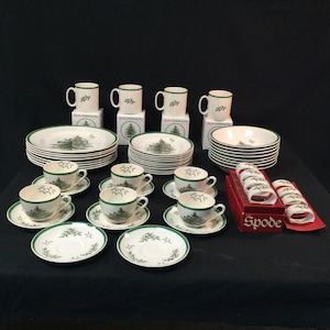 May include: A set of Spode Christmas Tree china, including mugs, teacups, saucers, dinner plates, salad plates, a serving bowl, and napkin rings. The china features a green Christmas tree design on a white background.