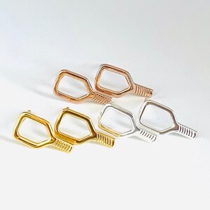 May include: Three pairs of small, paddle-shaped earrings in gold, rose gold, and silver.