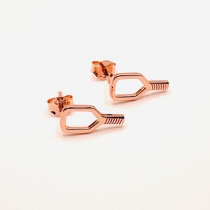 May include: A pair of rose gold earrings shaped like a paddle. The earrings are small and delicate.
