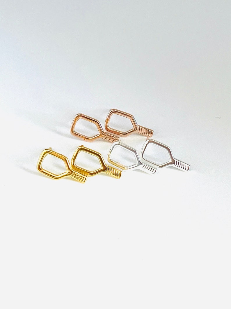 May include: Three pairs of small, paddle-shaped earrings in gold, rose gold, and silver.