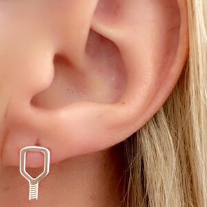 May include: A silver earring in the shape of a paddle.