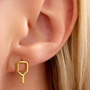 May include: Gold key-shaped earrings with a textured design.