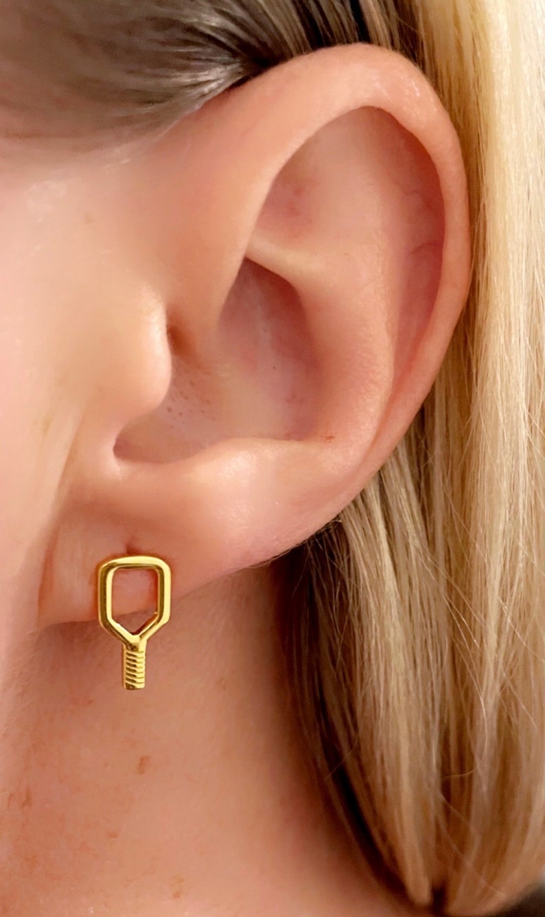 May include: Gold key-shaped earrings with a textured design.