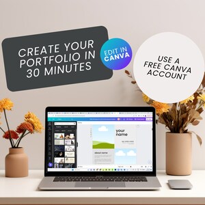 May include: A laptop computer displaying a Canva design template for a portfolio. The template has a blue sky background with white clouds and the text "your name" in a white box. The text "about name" is also visible in a smaller white box. The laptop is on a white table with two vases of dried flowers.