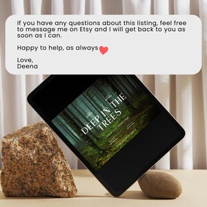 May include: A black tablet computer displaying a book cover with the title "Deep in the Trees" on a light brown surface with two rocks. The text on the tablet reads: "If you have any questions about this listing, feel free to message me on Etsy and I will get back to you as soon as I can. Happy to help, as always. Love, Deena."