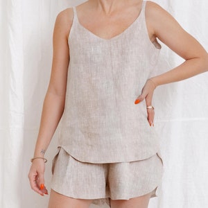 May include: A beige linen tank top and matching shorts set. The top has a v-neck and thin straps. The shorts have a relaxed fit.