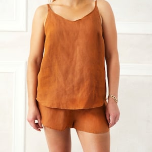 May include: A rust-colored linen tank top and matching shorts set. The top has a v-neck and thin straps. The shorts have a relaxed fit.